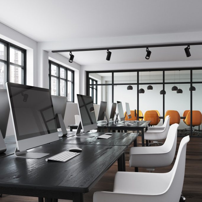 Modern office featuring a long black table with computers and bright orange chairs.