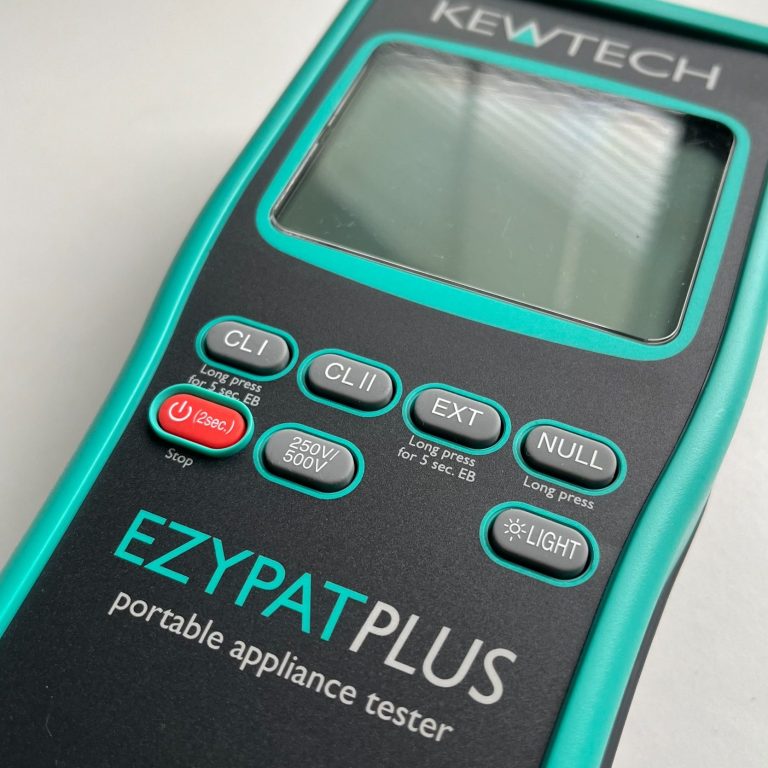A KEWTECH EZYPAT PLUS portable appliance tester with buttons and a screen.